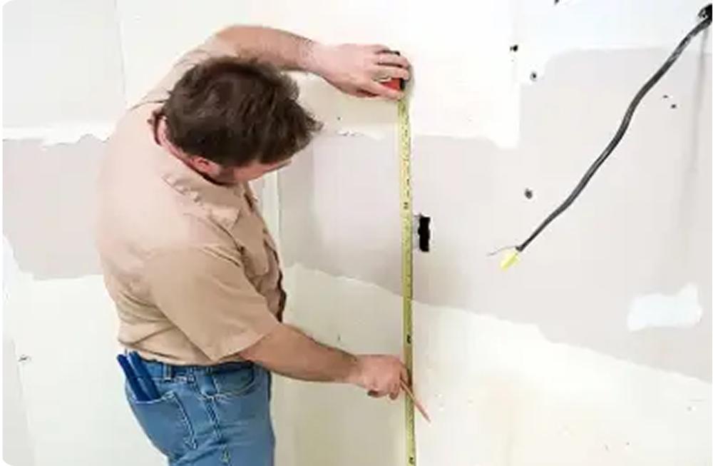 Worker measuring wall
